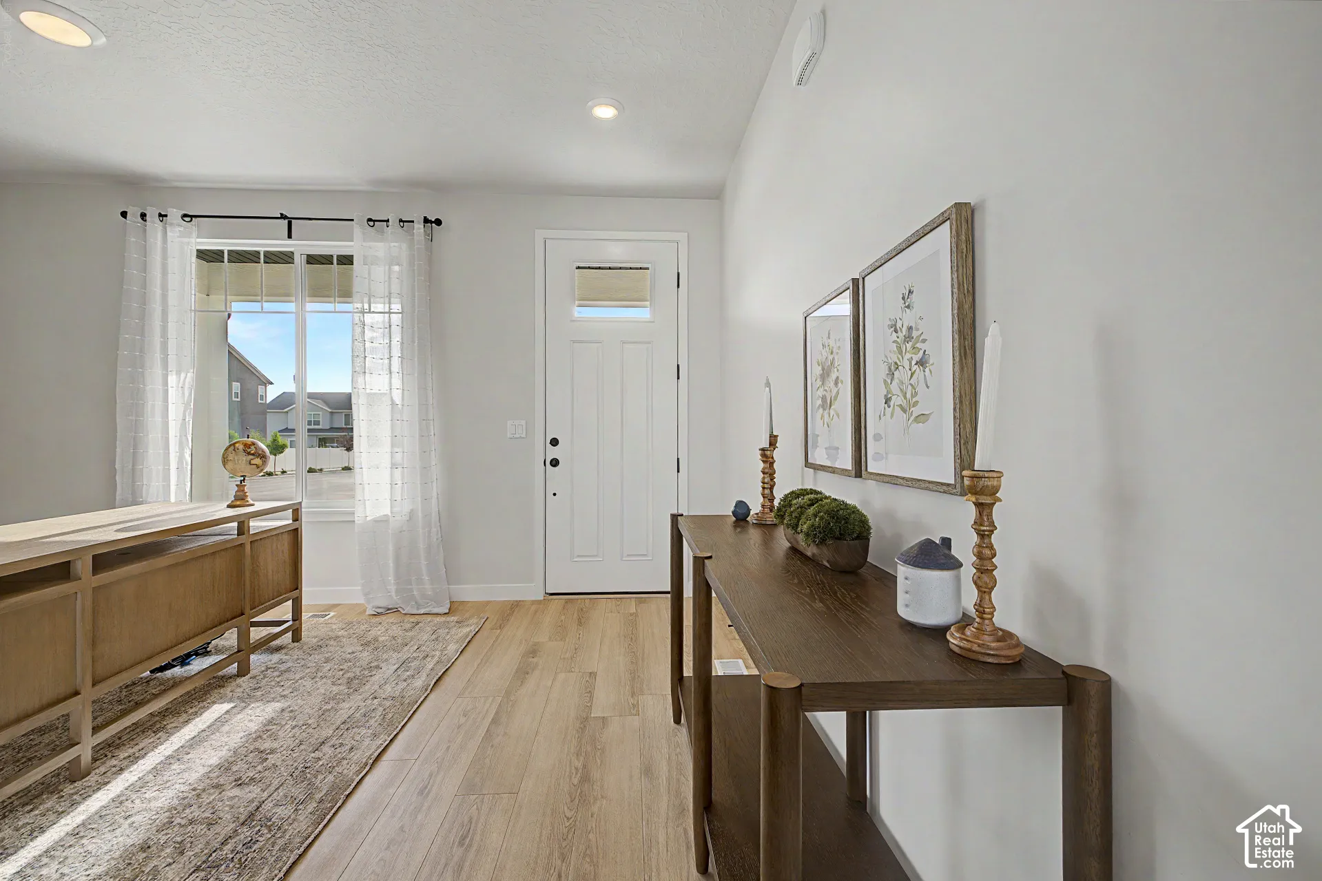 White paneled entry door with transom window, recessed lighting, and wood-finish flooring