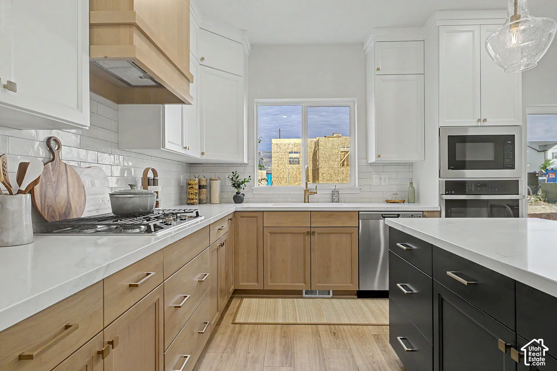 Contemporary kitchen with two-tone cabinetry, white countertops, built-in stainless steel appliances, and a gas cooktop