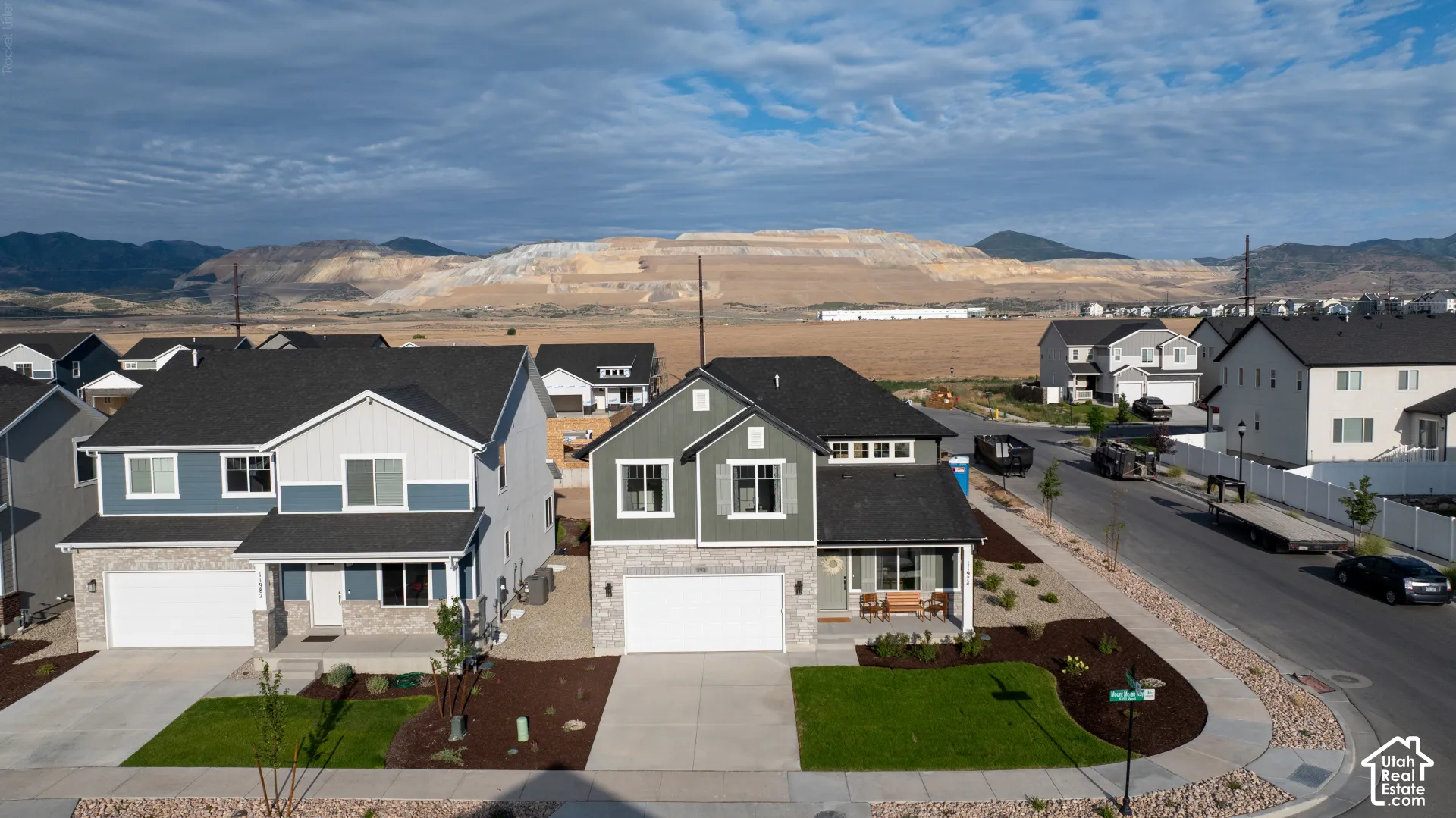 Two-story residence featuring a gray exterior with stone accents, a two-car garage, and a covered front porch