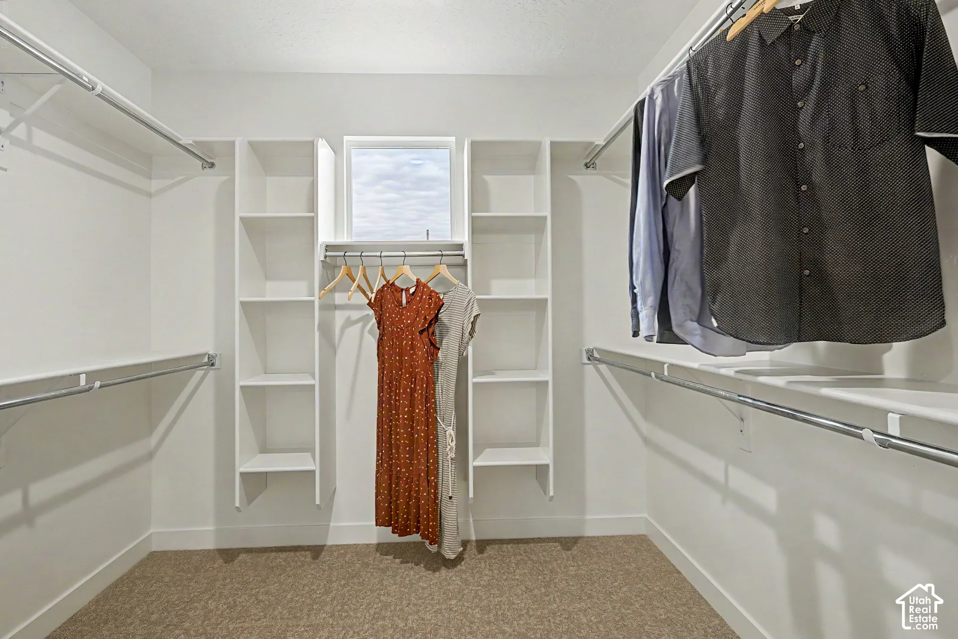 Walk-in closet featuring built-in shelving, multiple hanging rods, a window, and carpet flooring