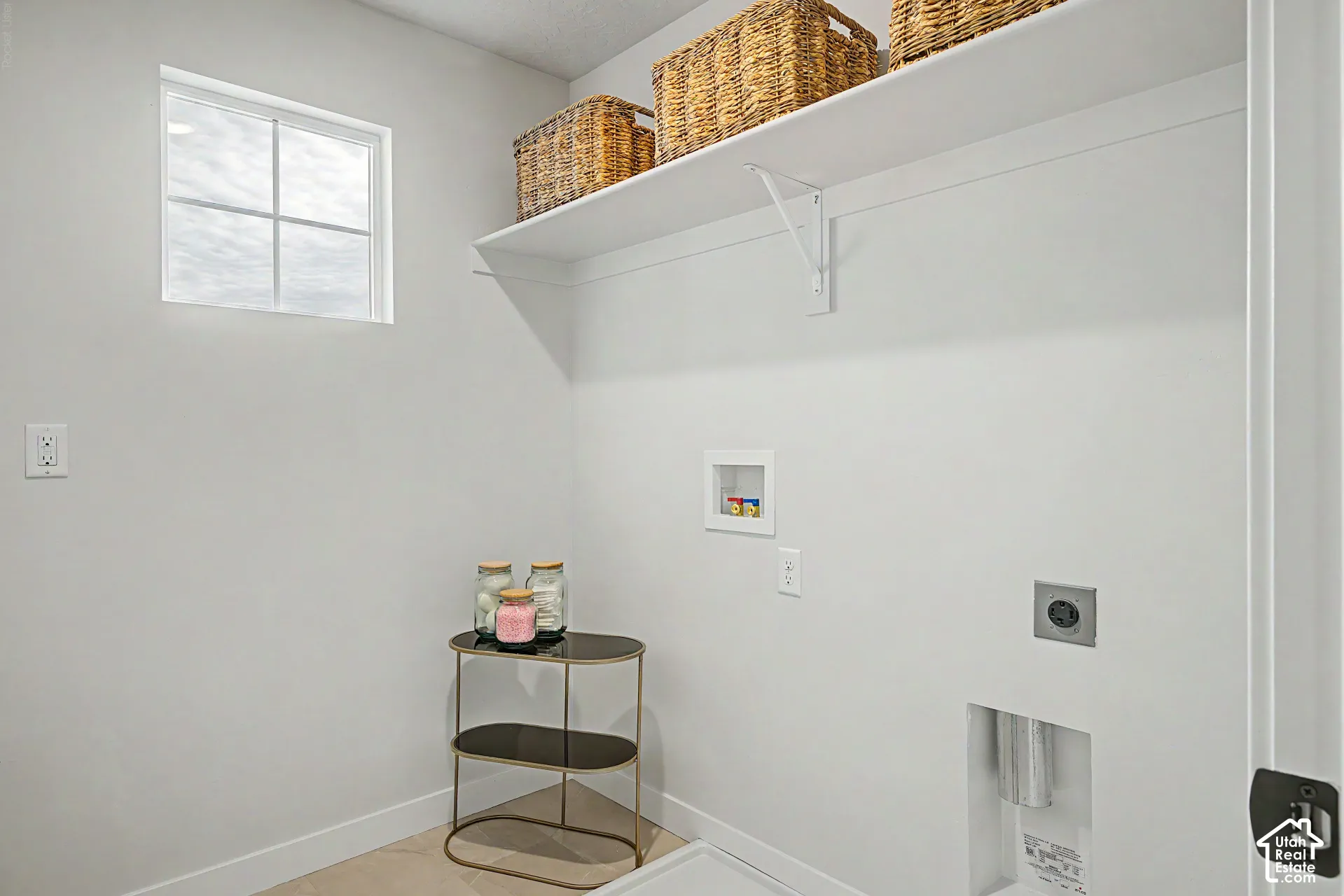 White overhead shelving, square window, utility hookups, and light-colored flooring