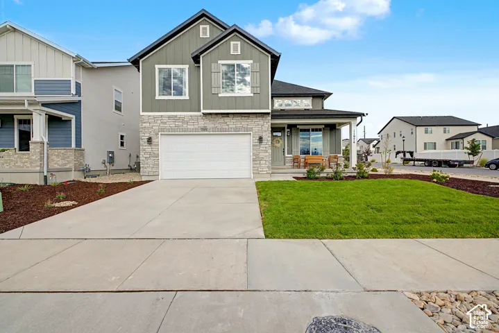 Two-story exterior featuring stone accents, a concrete driveway, and a covered porch