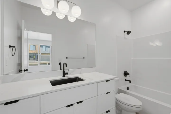 White vanity with an integrated sink, white countertop, and matte black fixtures