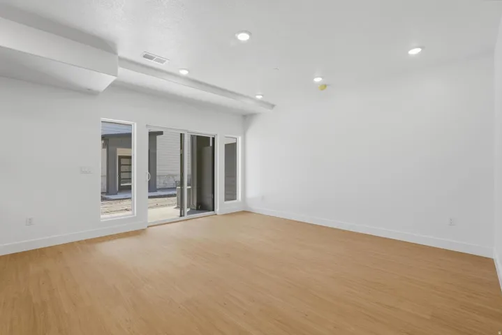 Recessed lighting, light wood-finish flooring, white walls, and a sliding glass door with side windows