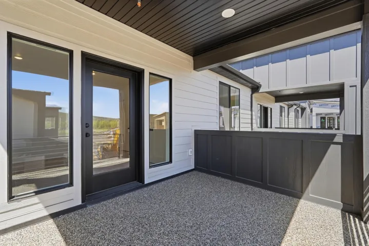 Covered patio with a textured flooring, white horizontal siding, and dark accent panels