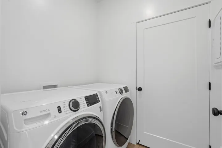 Laundry area with a front-loading washer and dryer, white walls, and a white interior door with black hardware