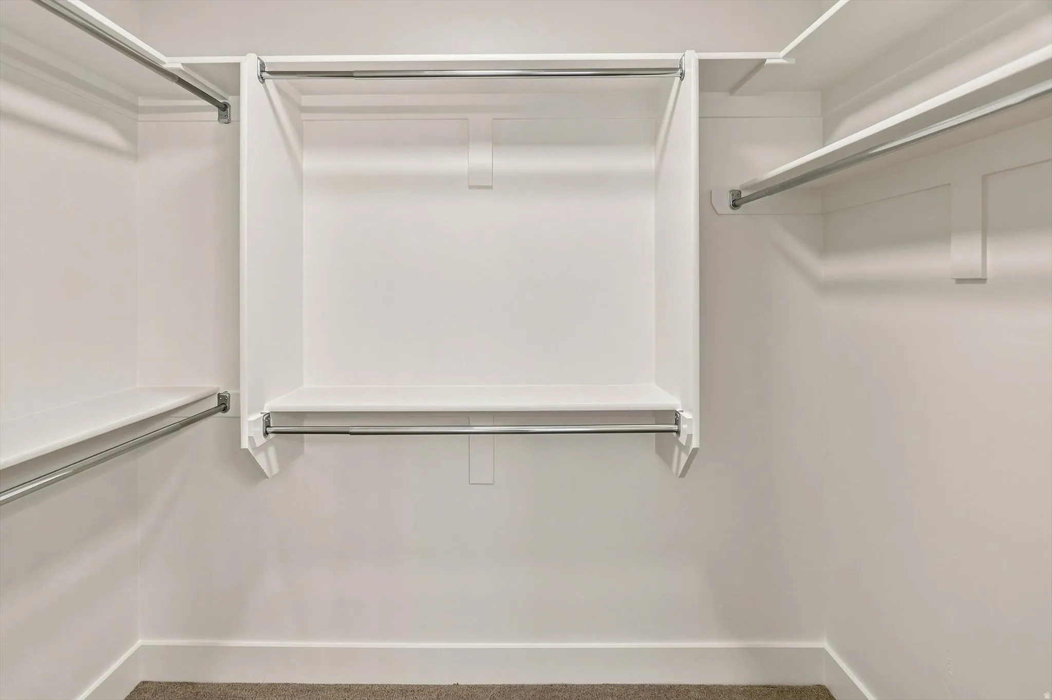 White built-in shelving, chrome hanging rods, and carpet flooring