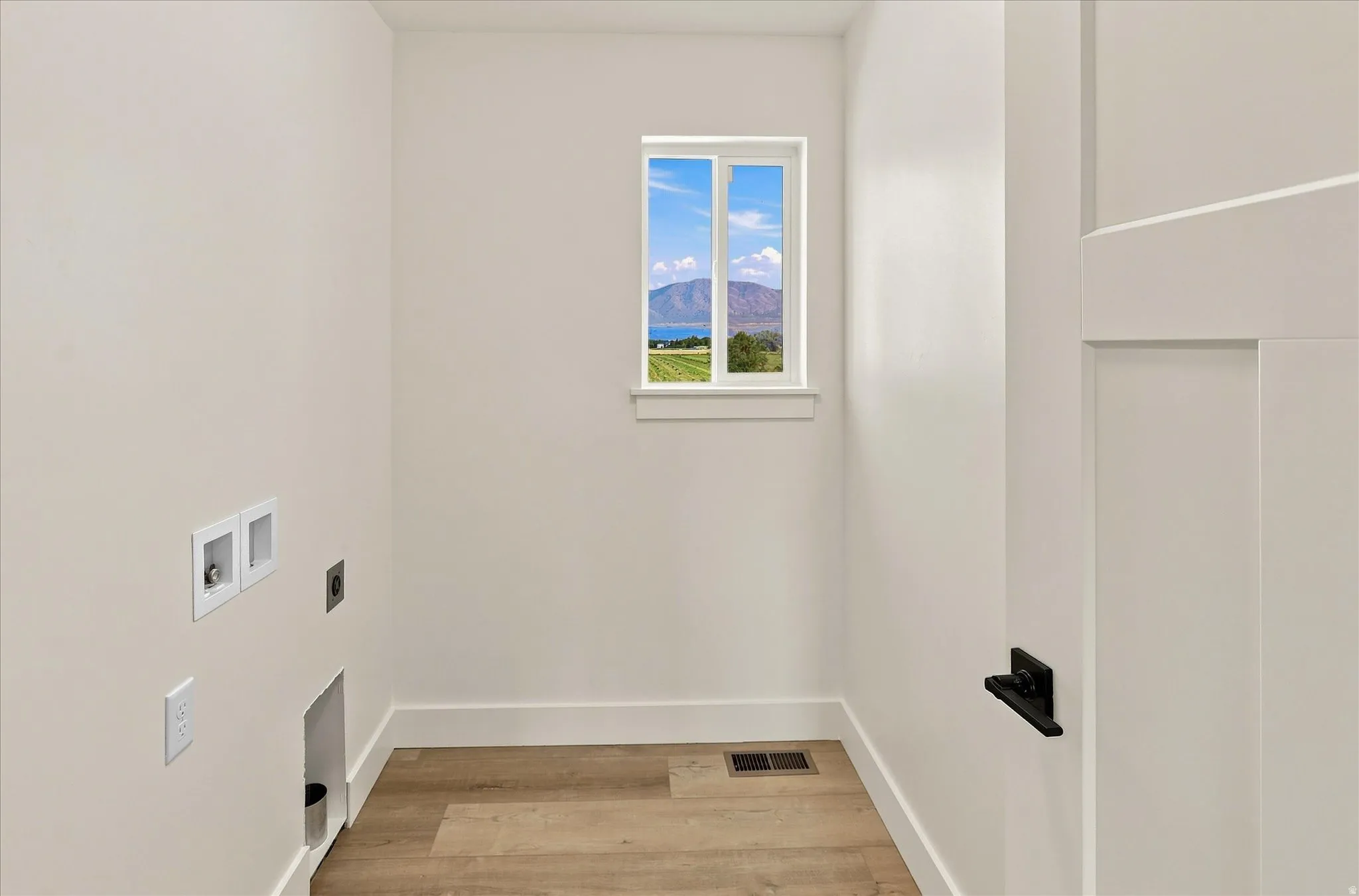 Bright interior with a rectangular window, wood-finish flooring, and white trim