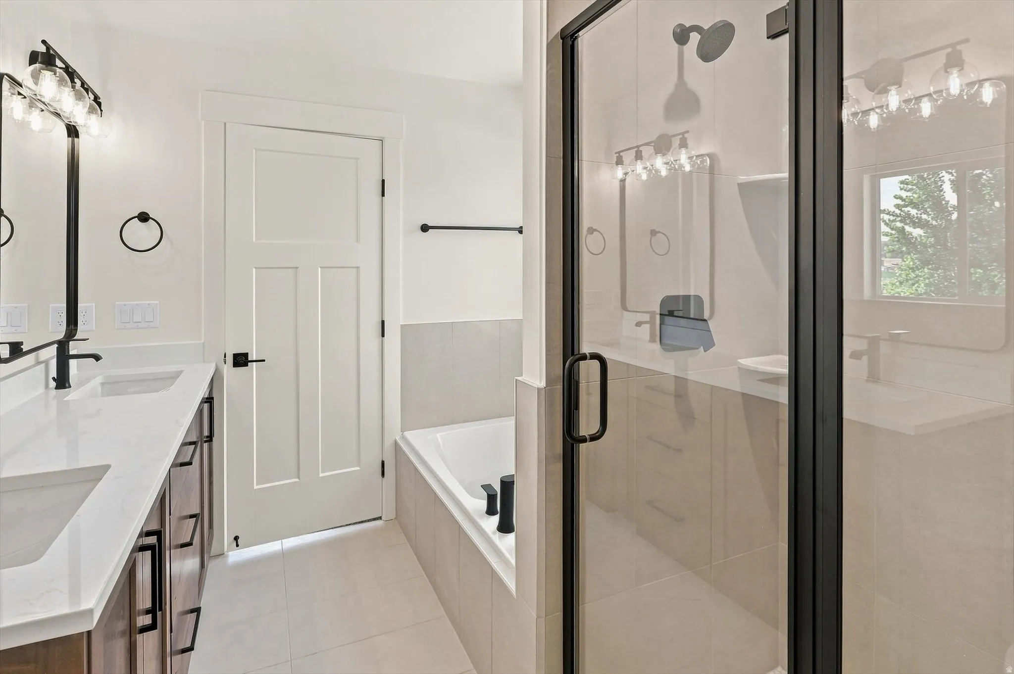 Dual vanity with white countertops, matte black fixtures, and wood-finish cabinetry