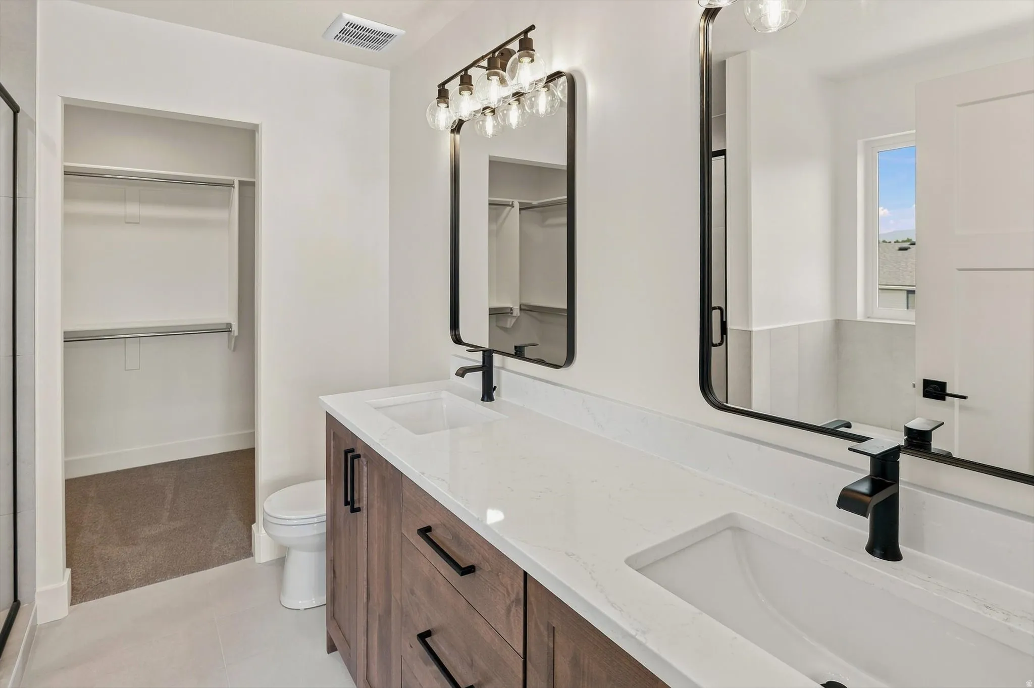 Double vanity with white countertops, undermount sinks, and matte black fixtures