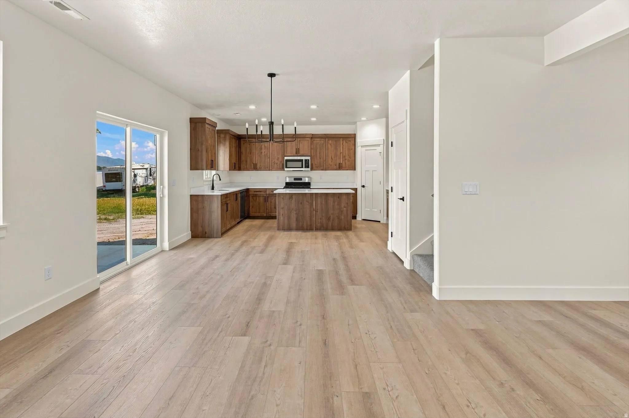 Open-concept kitchen with wood-finish cabinetry, stainless steel appliances, and a central island