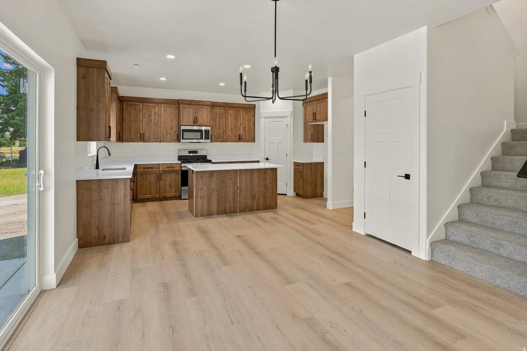 Open-concept kitchen with wood cabinetry, white countertops, and a central island