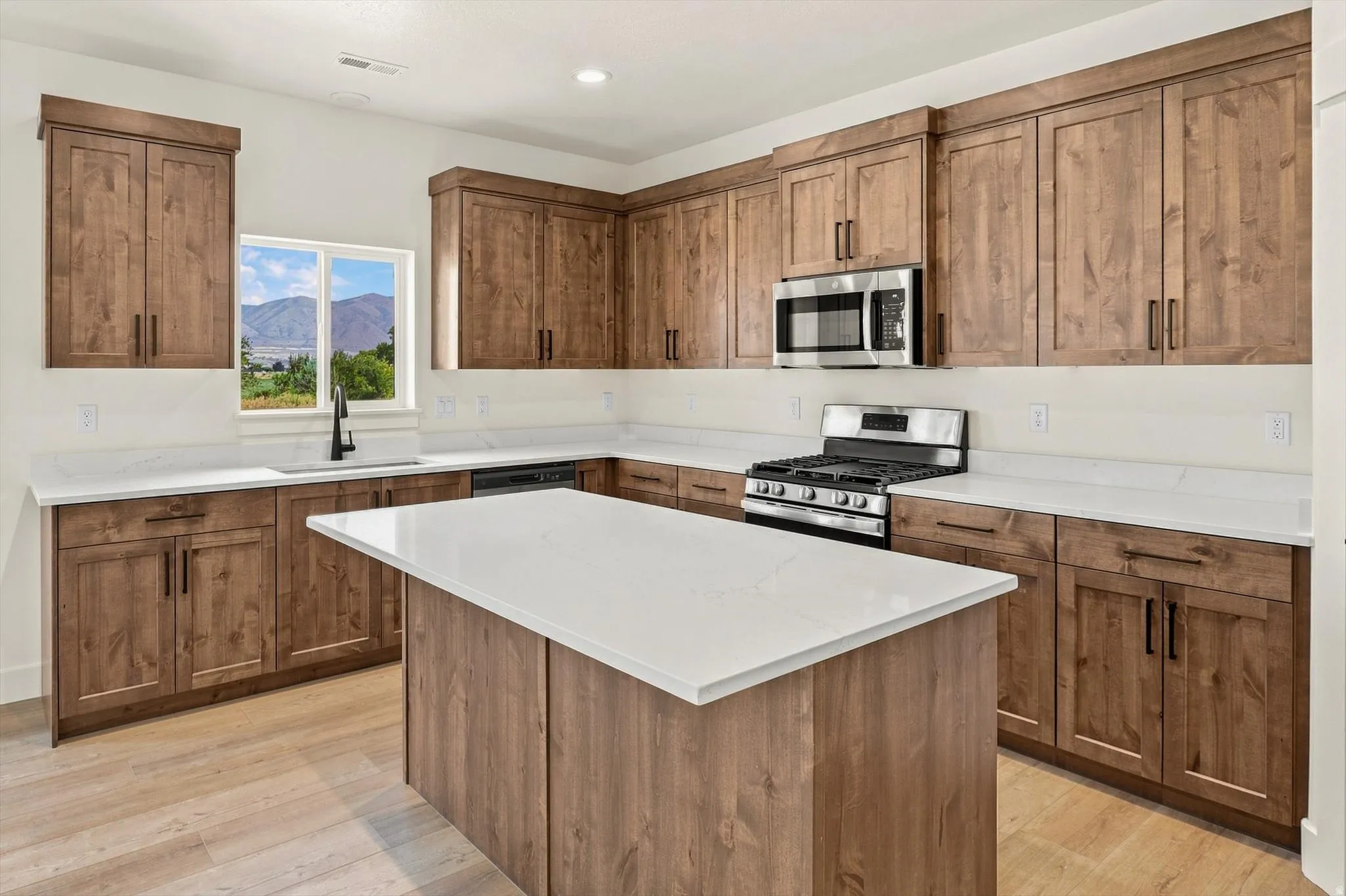 Kitchen featuring wood-finish cabinetry, white countertops, stainless steel appliances, and a central island