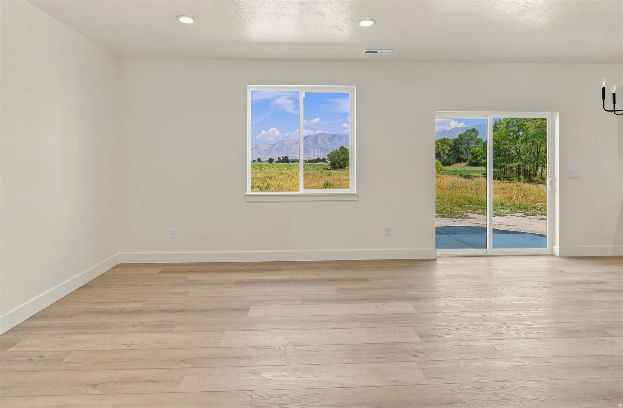 Recessed lighting, wood-finish flooring, white walls, large window, and sliding glass door