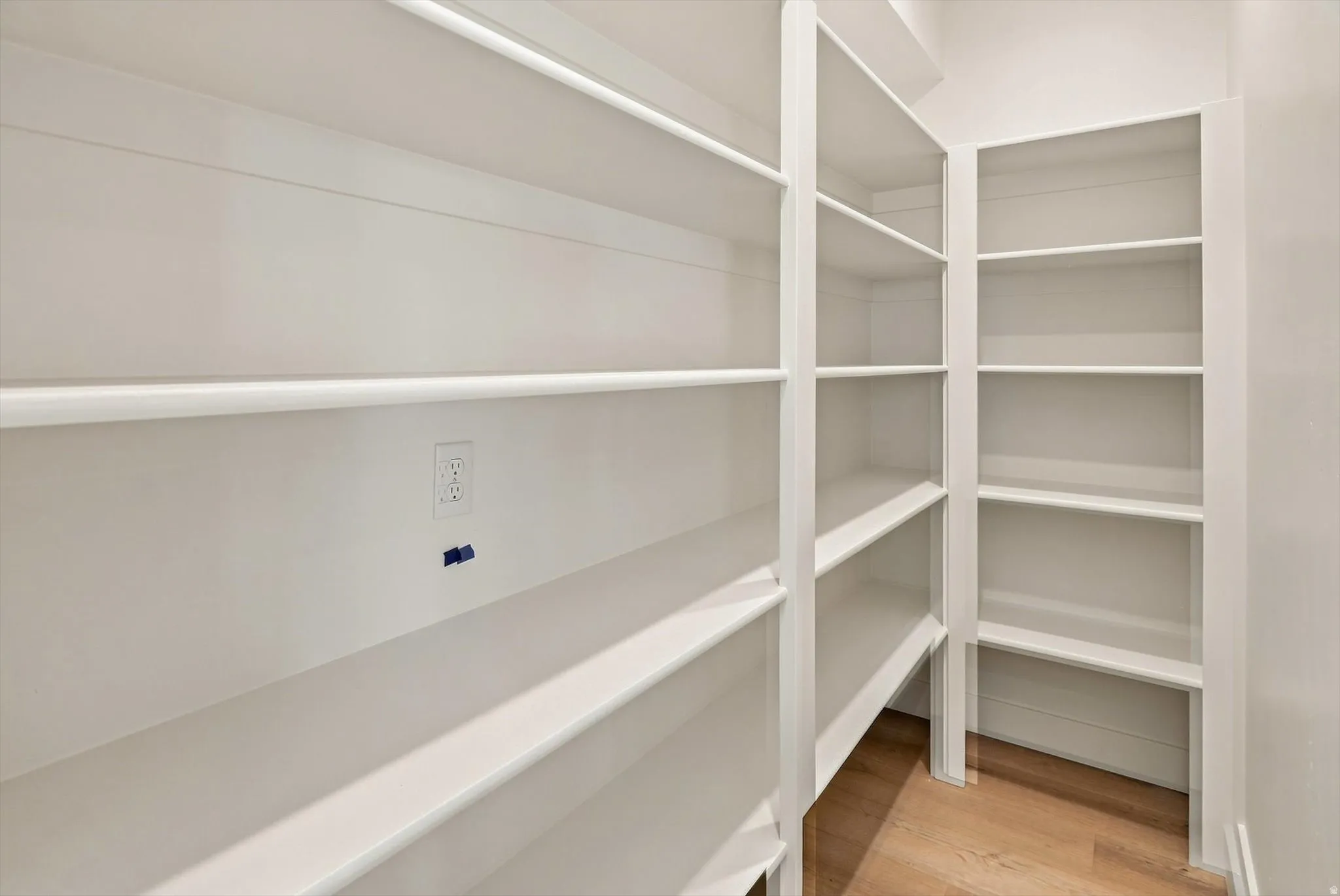 Built-in shelving with multiple storage levels, light wood-finish flooring, and white wall finishes