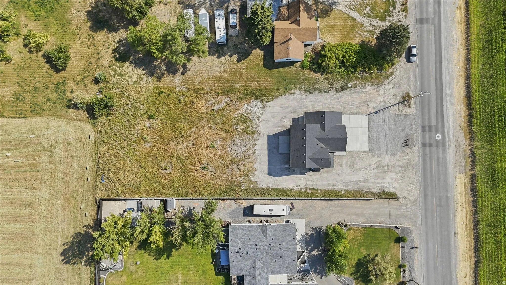 Single-story residence featuring a dark shingled roof, concrete driveway, and surrounding gravel landscaping