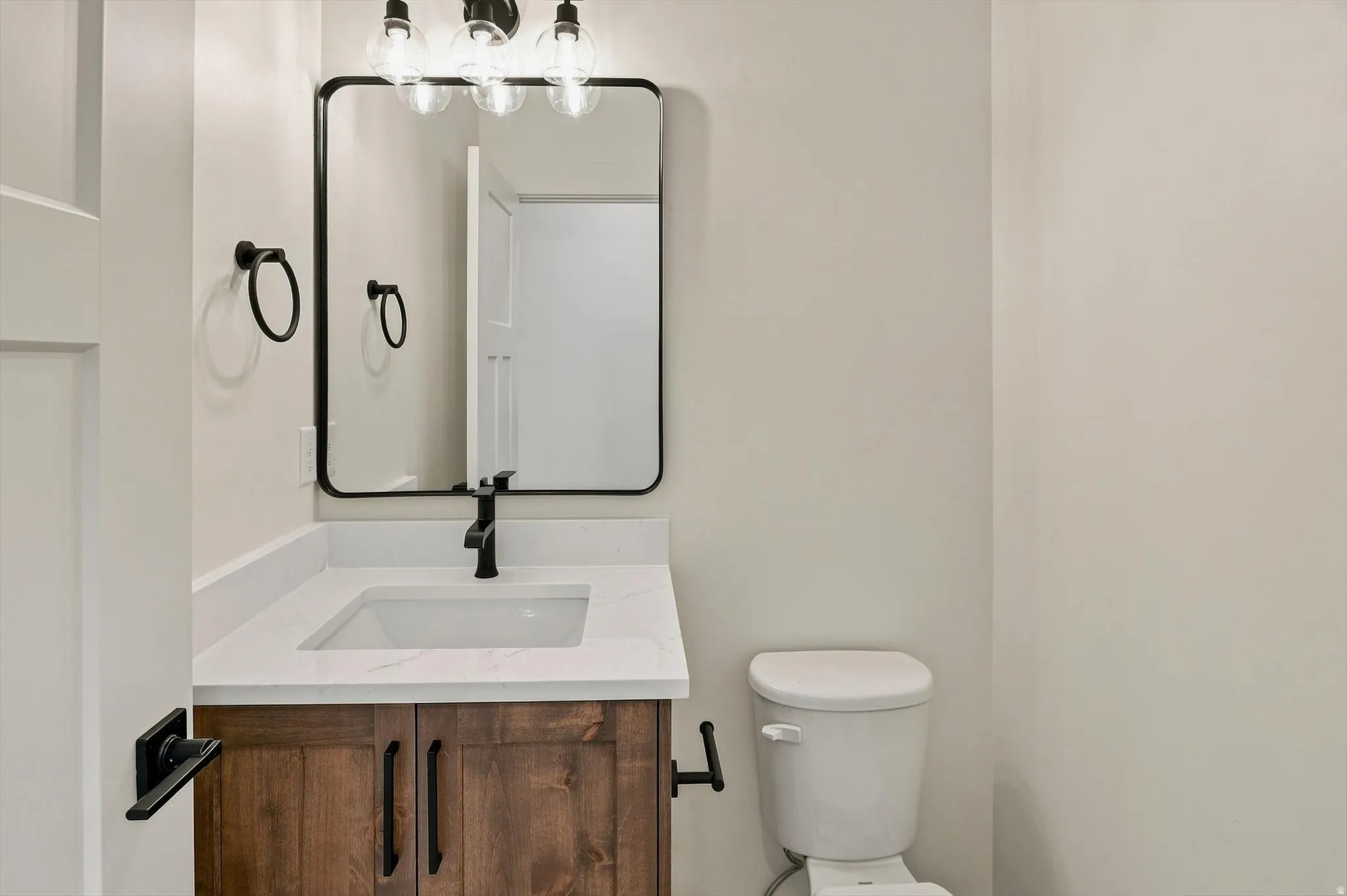 Wood-finish vanity with an integrated sink, white countertop, and matte black faucet