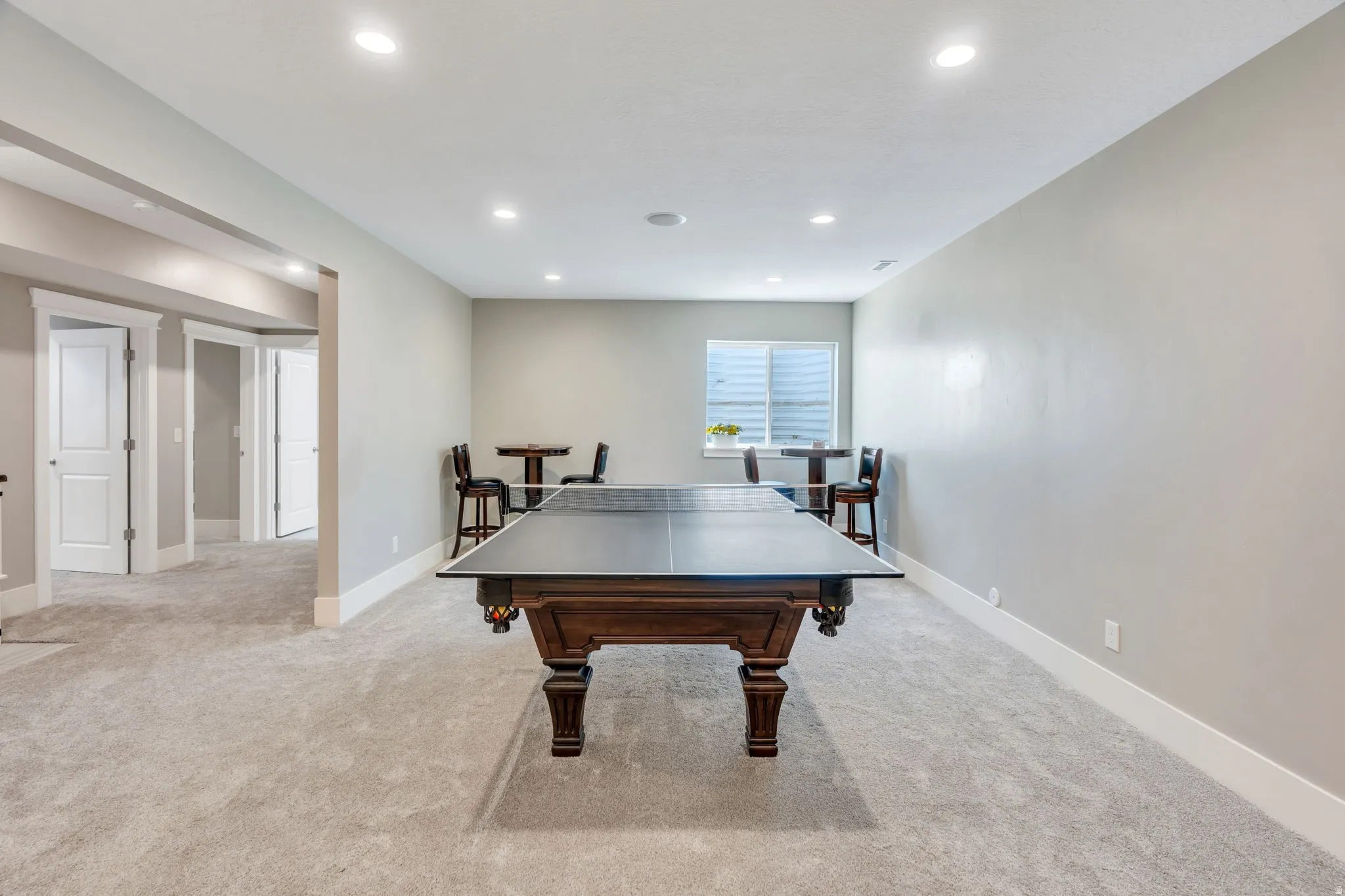 Expansive carpeted room with recessed lighting and a window with blinds