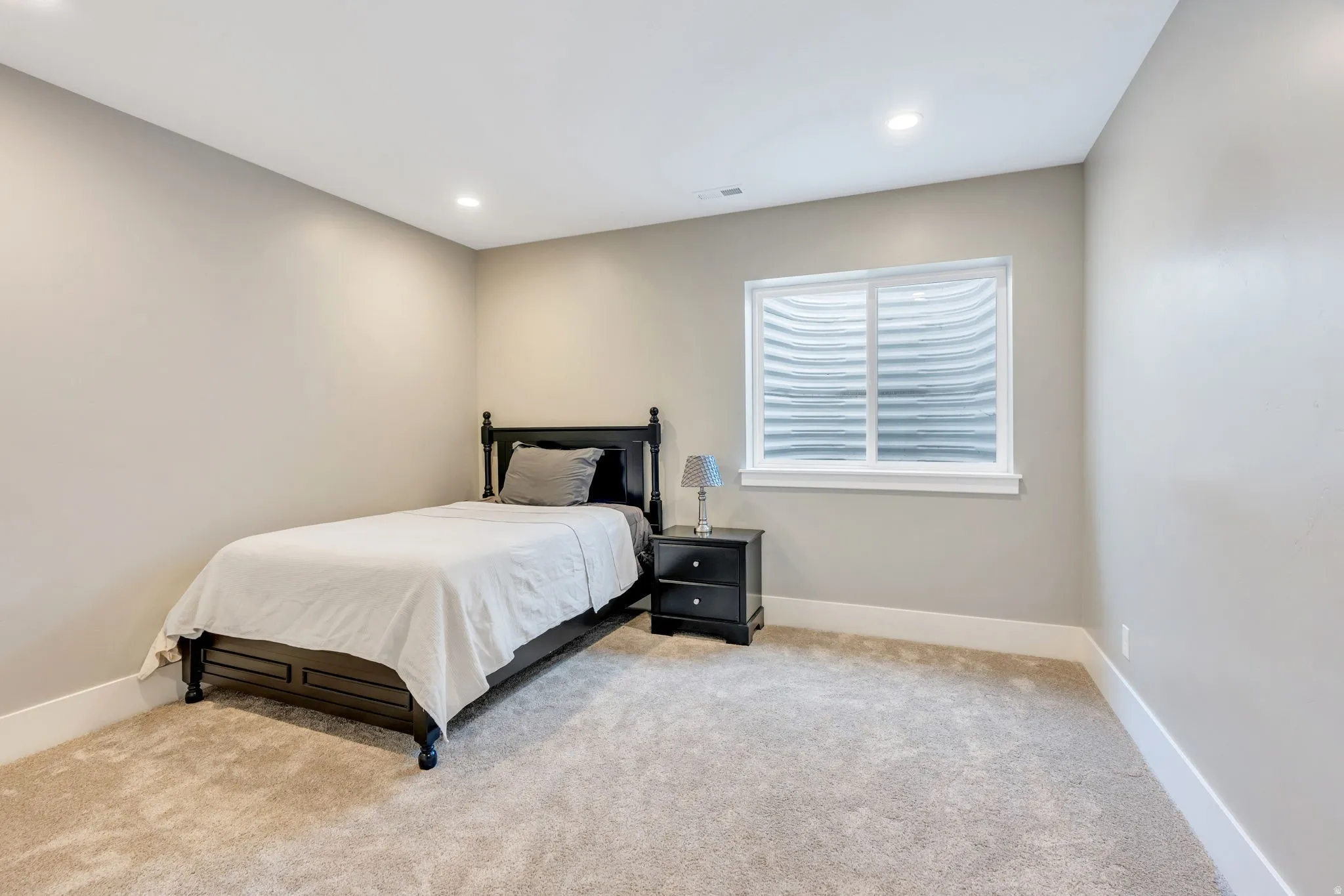Recessed ceiling lighting, neutral wall tones, white trim, and a window with white casing