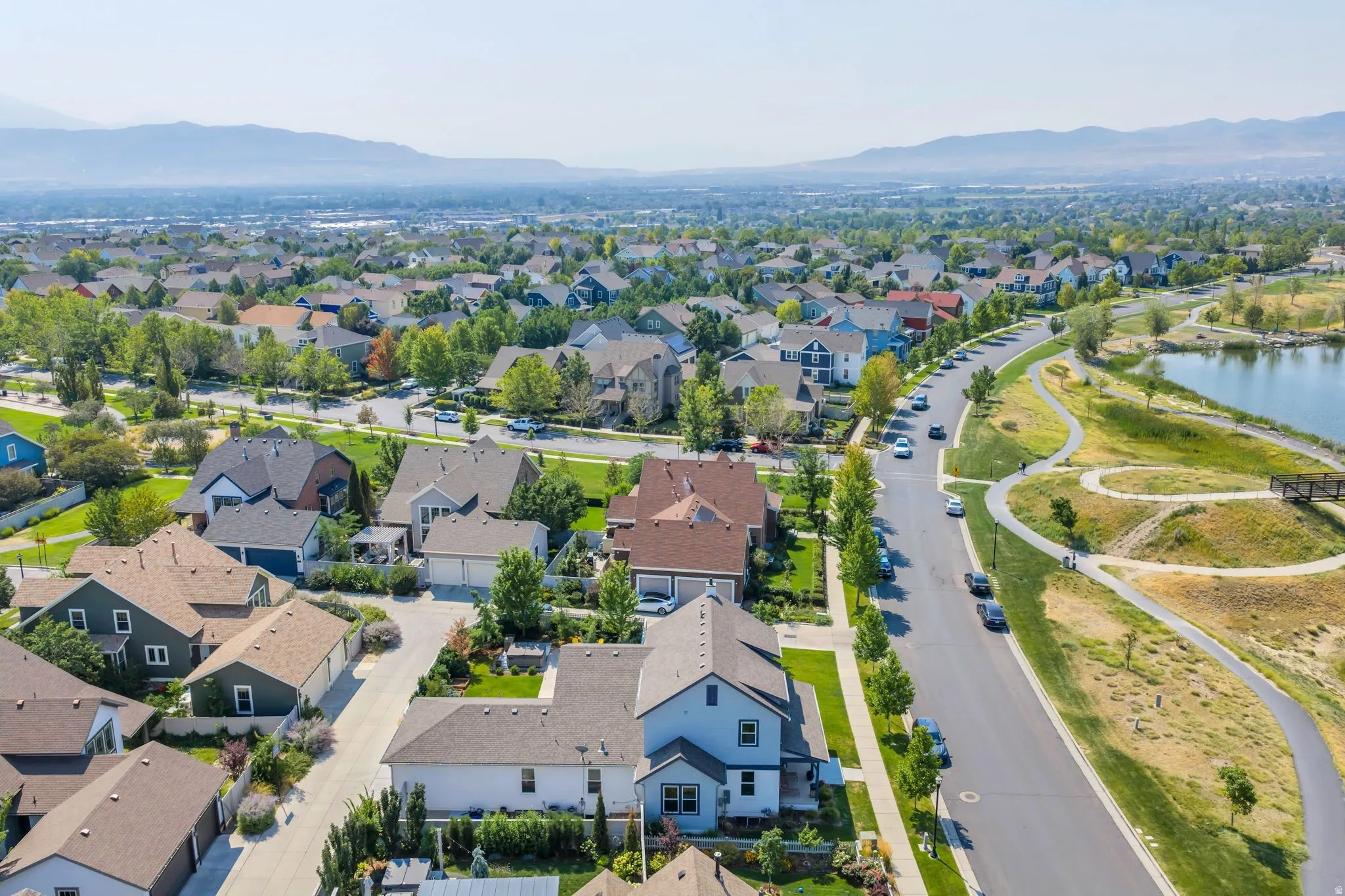Aerial perspective showcasing a residential neighborhood with diverse architectural styles, a paved street, and landscaped green spaces