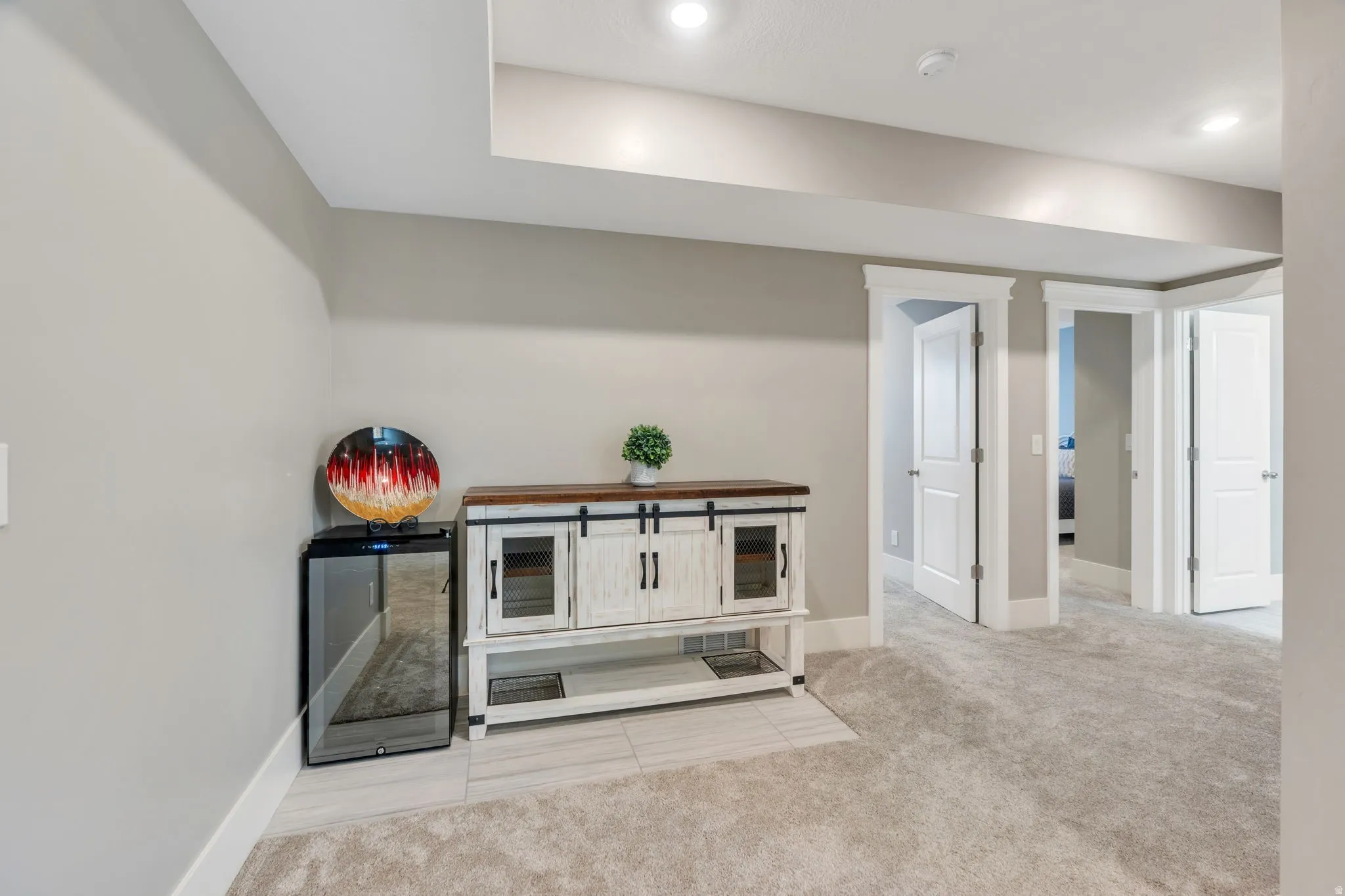 Recessed ceiling lighting, light gray wall tones, white trim, and light gray carpeting
