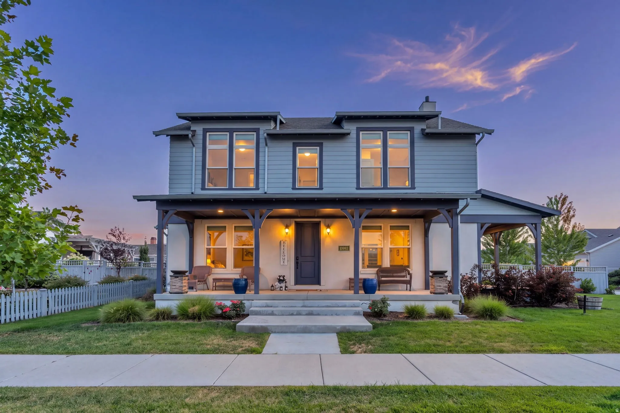 Two-story residence featuring light blue siding with white trim, a covered front porch, and a sidewalk