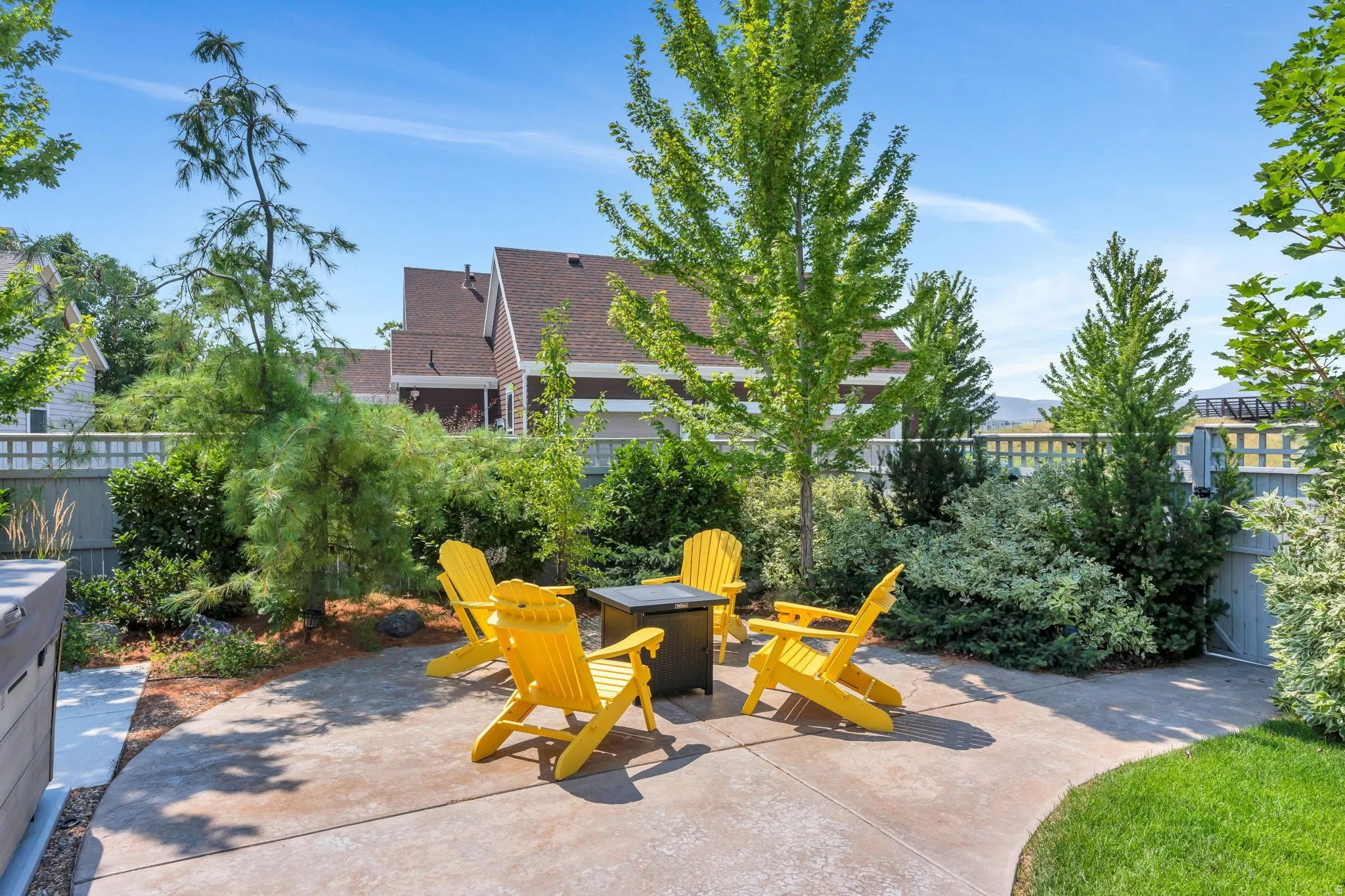Expansive patio area with concrete surfacing, surrounded by manicured landscaping and mature trees