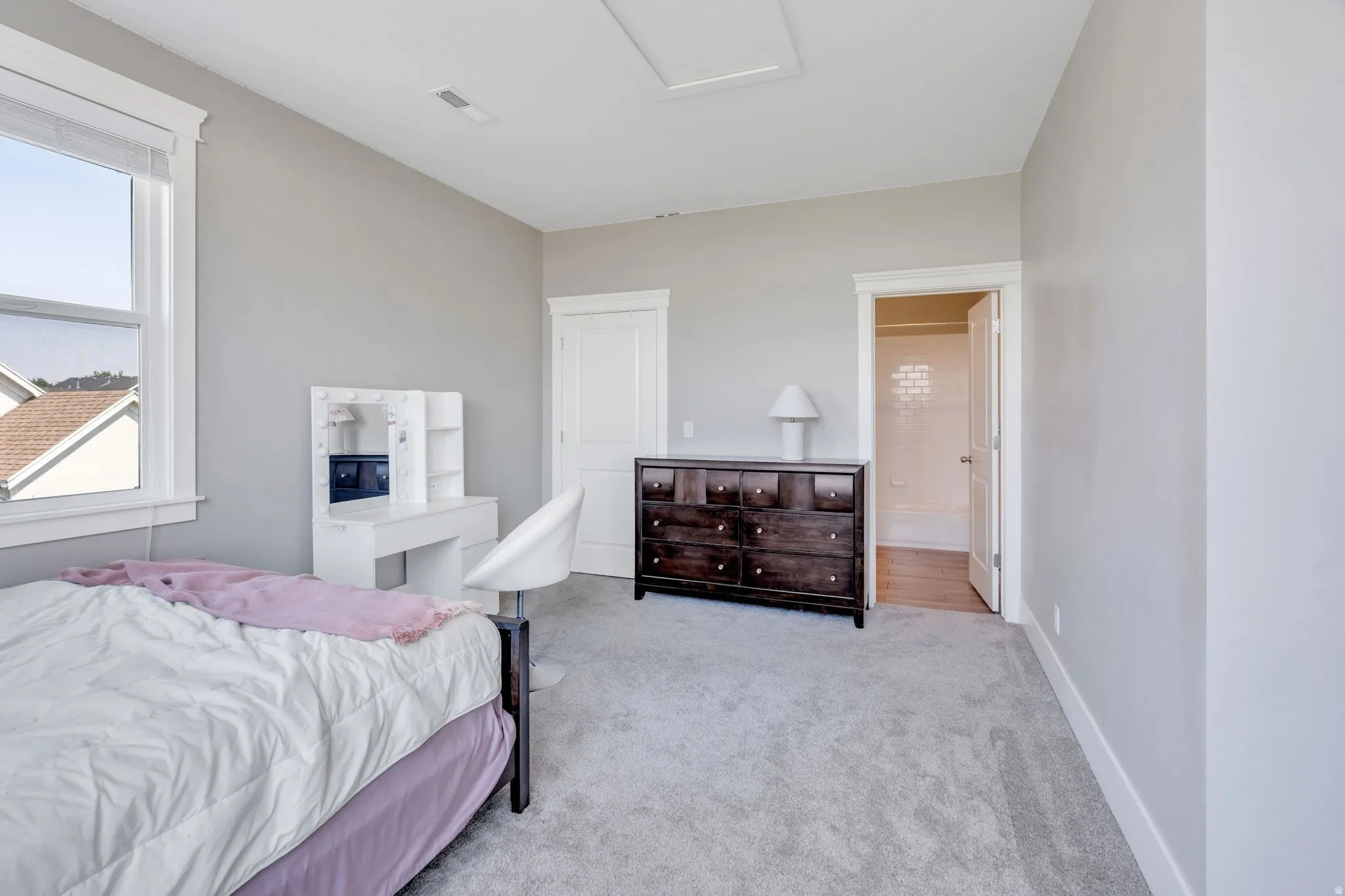 Neutral wall paint finish, white trim, light-colored carpeting, window with white frame, and a white interior door