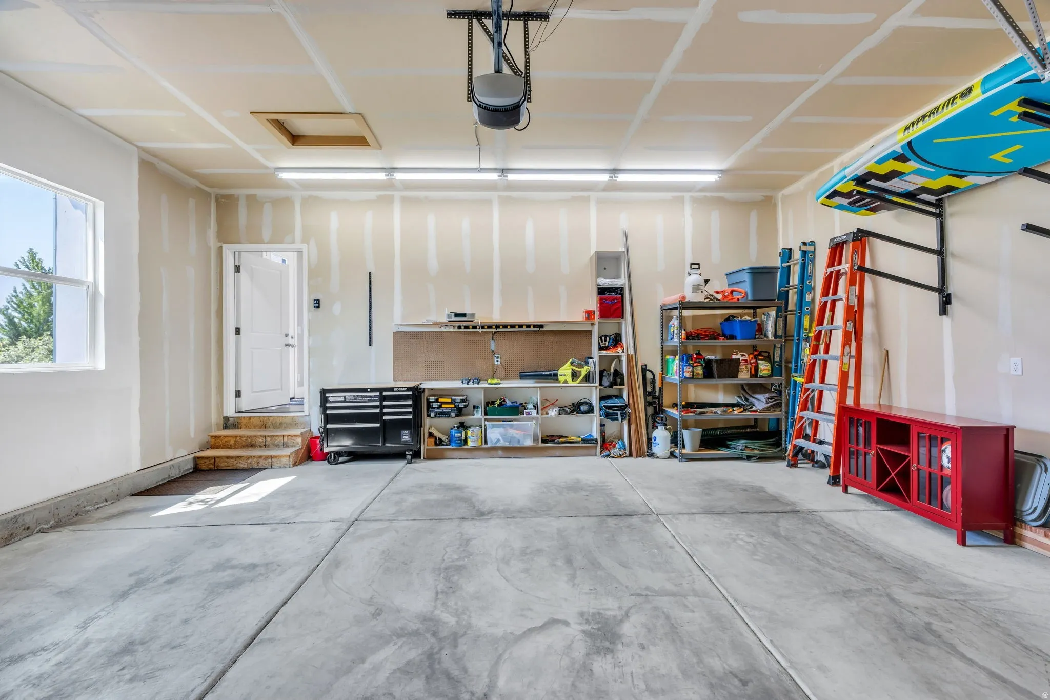 Concrete flooring with visible seams, overhead lighting, and a single window