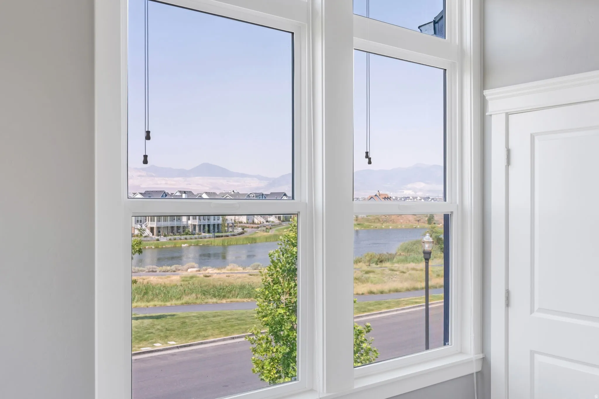 Large windows with white trim, offering a water feature and distant mountain scenery