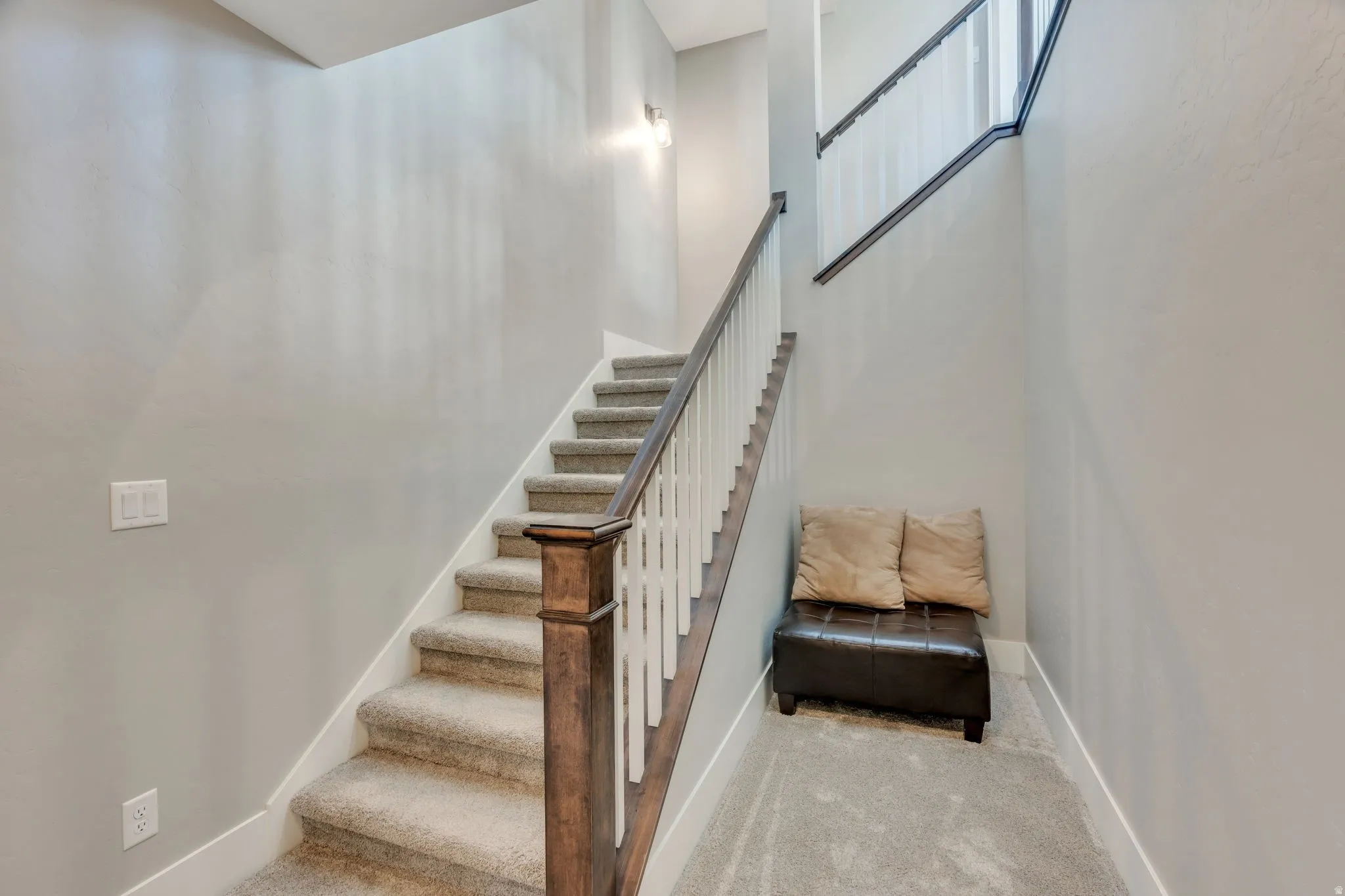 Carpeted staircase featuring a wood newel post and railings with white spindles