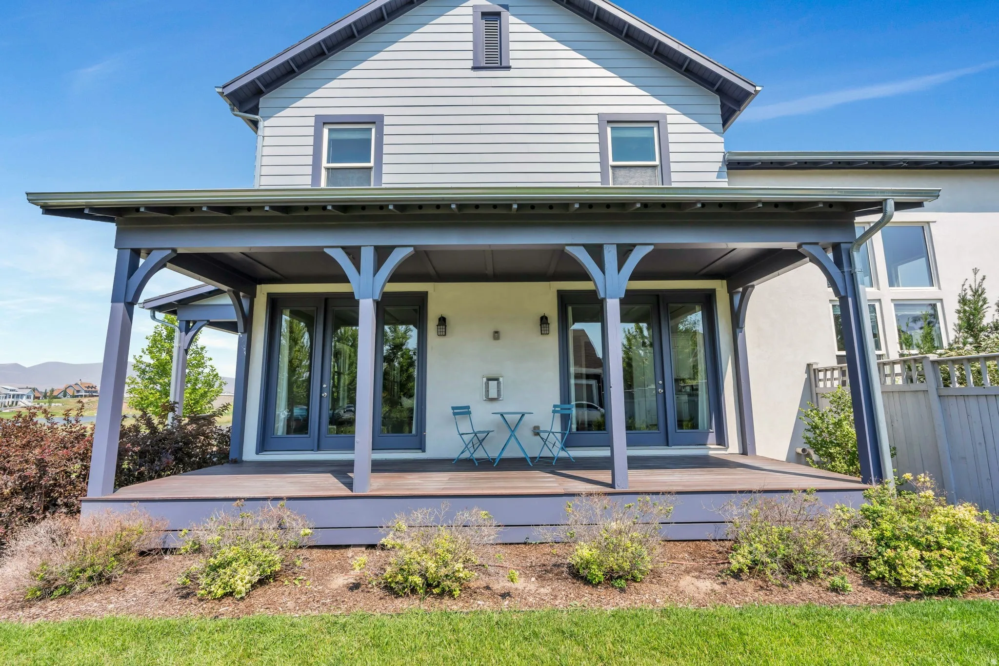 Covered porch with decorative arched supports, dual exterior wall sconces, and dual-pane double French doors