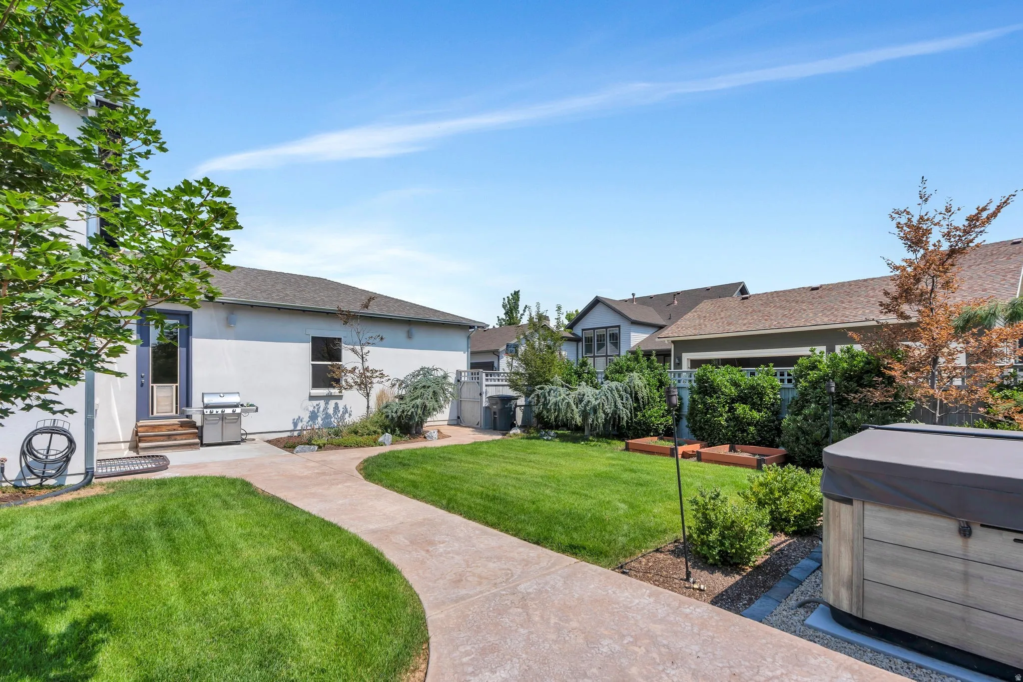 Expansive lawn with a winding concrete pathway, mature trees, and landscaping