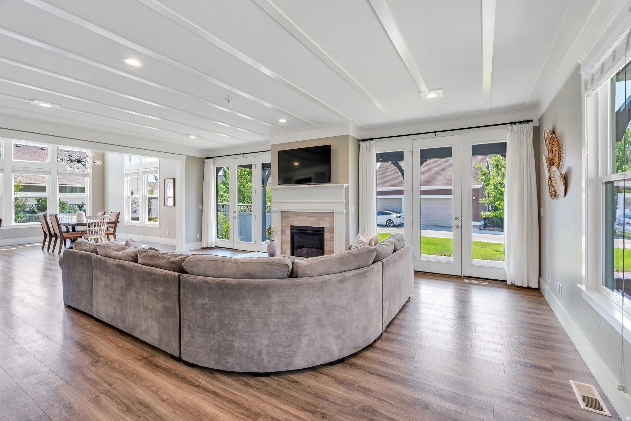 Expansive living area featuring wood-finish flooring, a coffered ceiling with recessed lighting, and a fireplace with a mantel