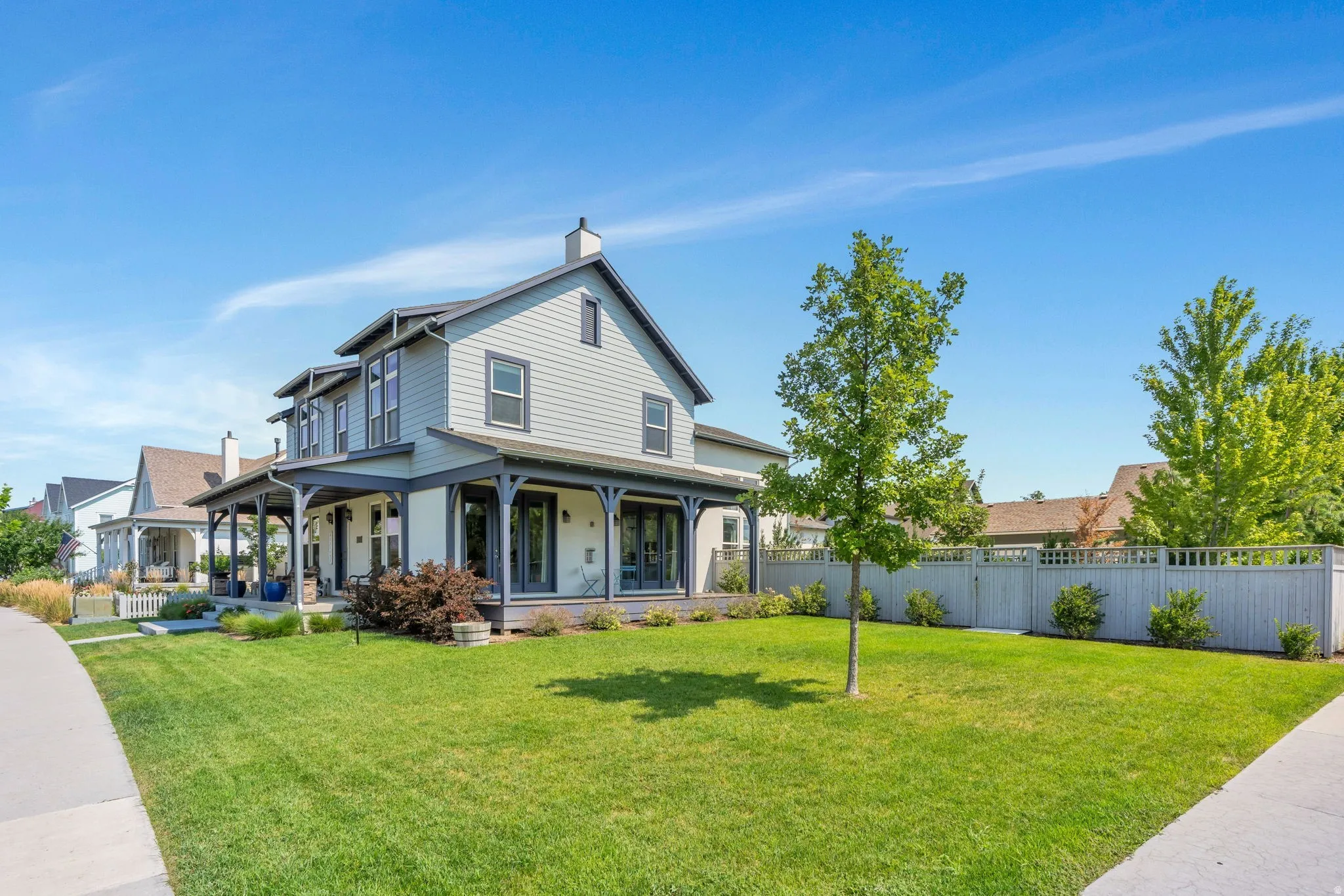 Two-story home with a light-colored siding exterior, dark trim, and a covered porch
