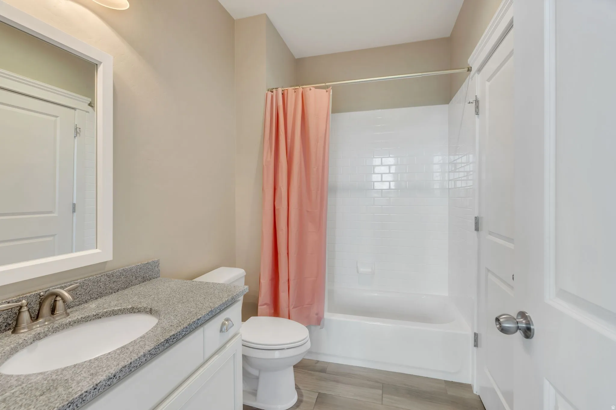 White vanity with a speckled countertop, undermount sink, and brushed nickel faucet