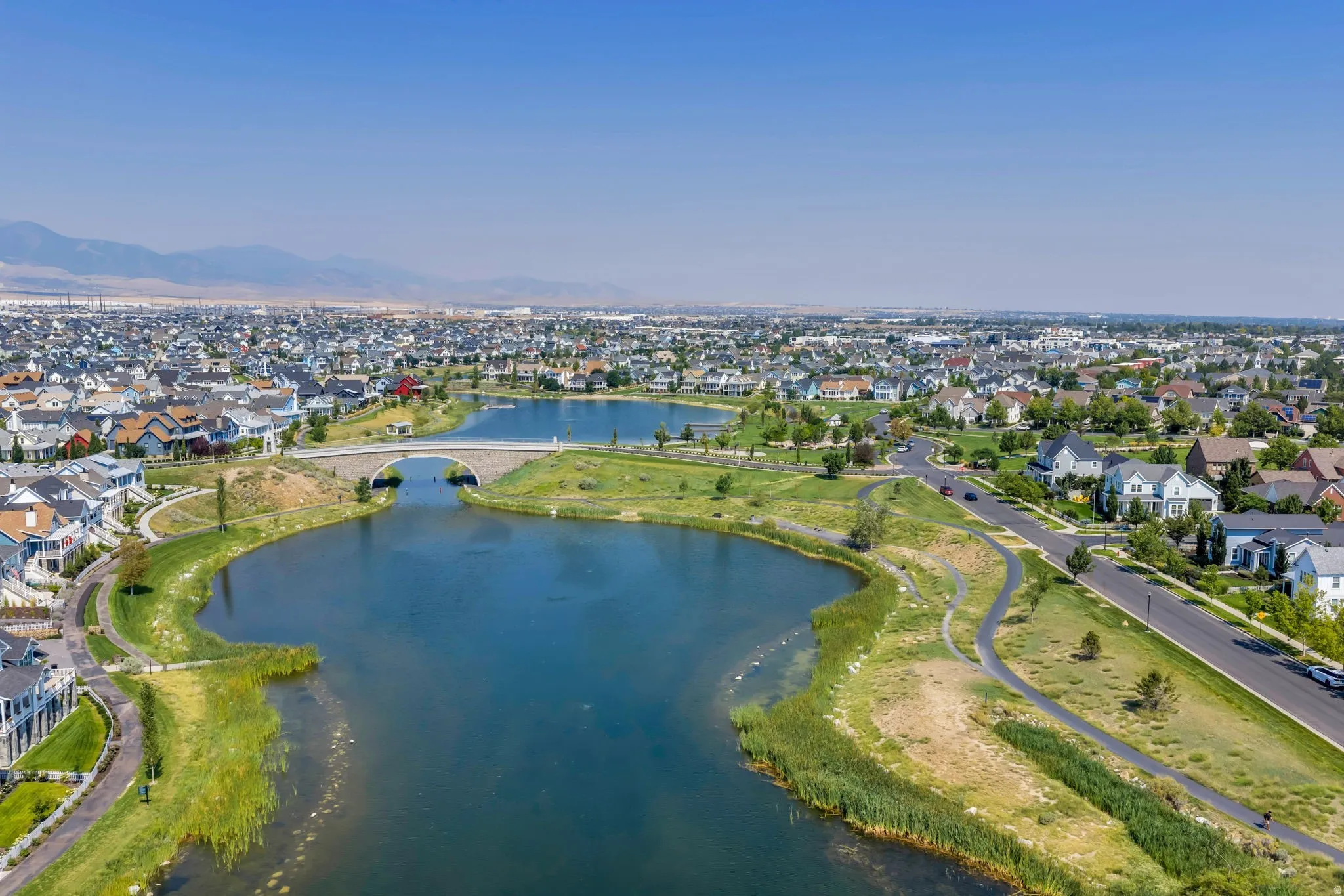 Community setting featuring multiple bodies of water, pedestrian pathways, and a stone bridge