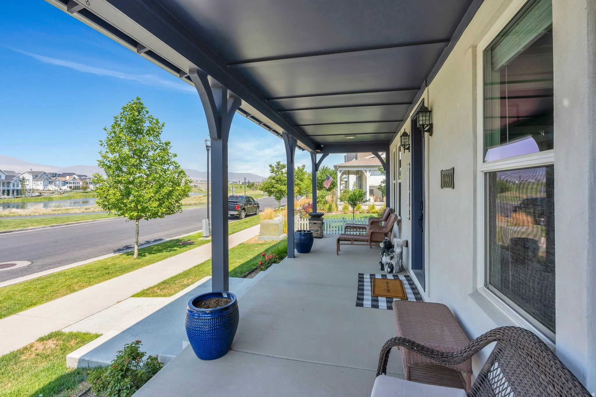 Covered front porch with solid roof, concrete flooring, exterior wall sconces, and white stucco siding