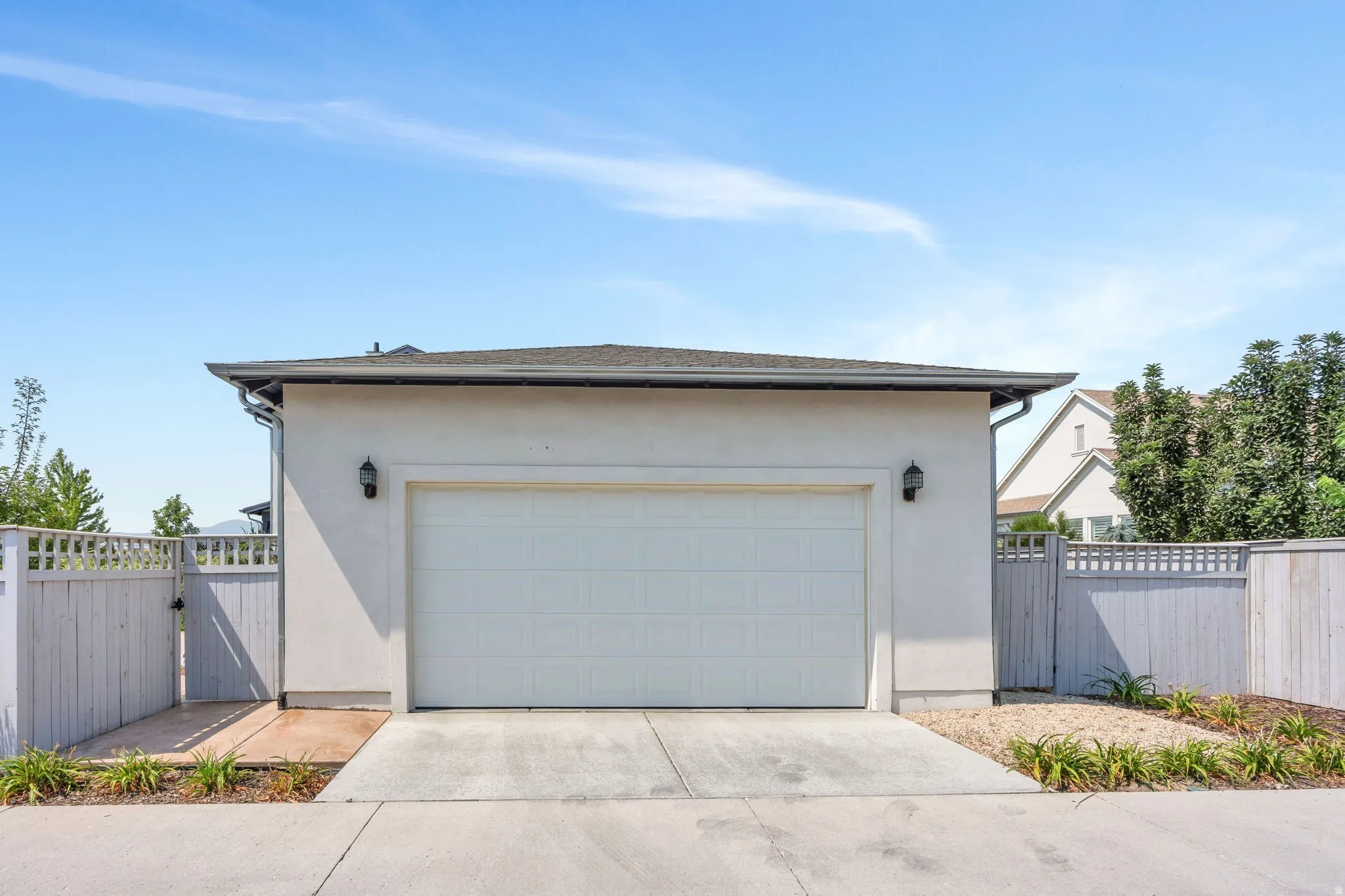 Attached single-car garage with a panel door, stucco exterior, and concrete driveway