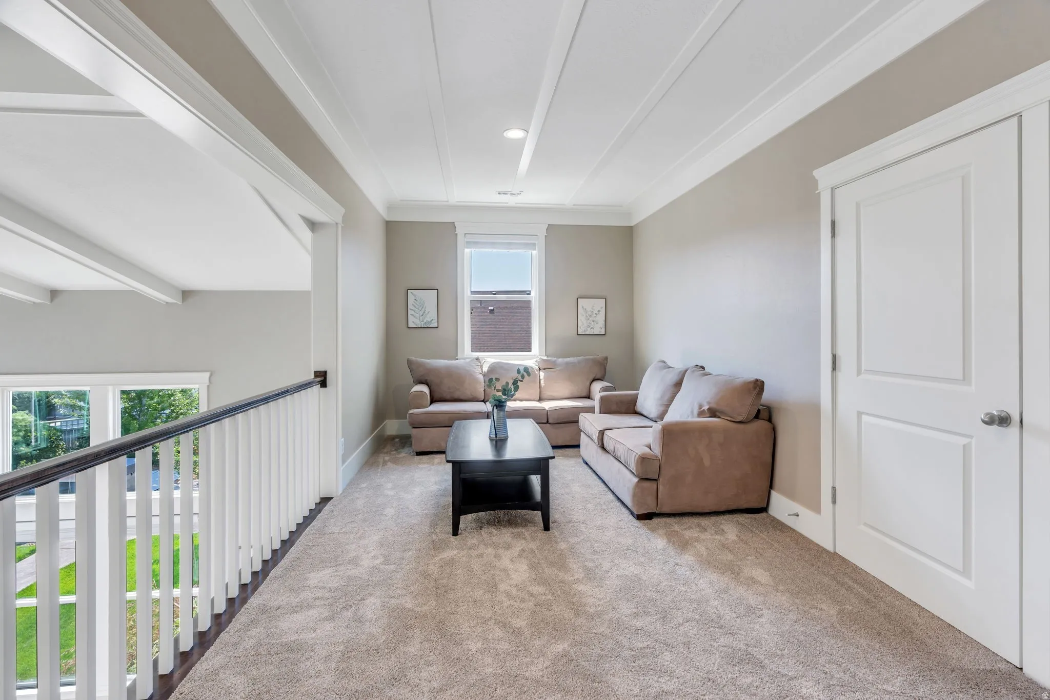 Carpeted loft area featuring a window, painted wood trim, and a white paneled door