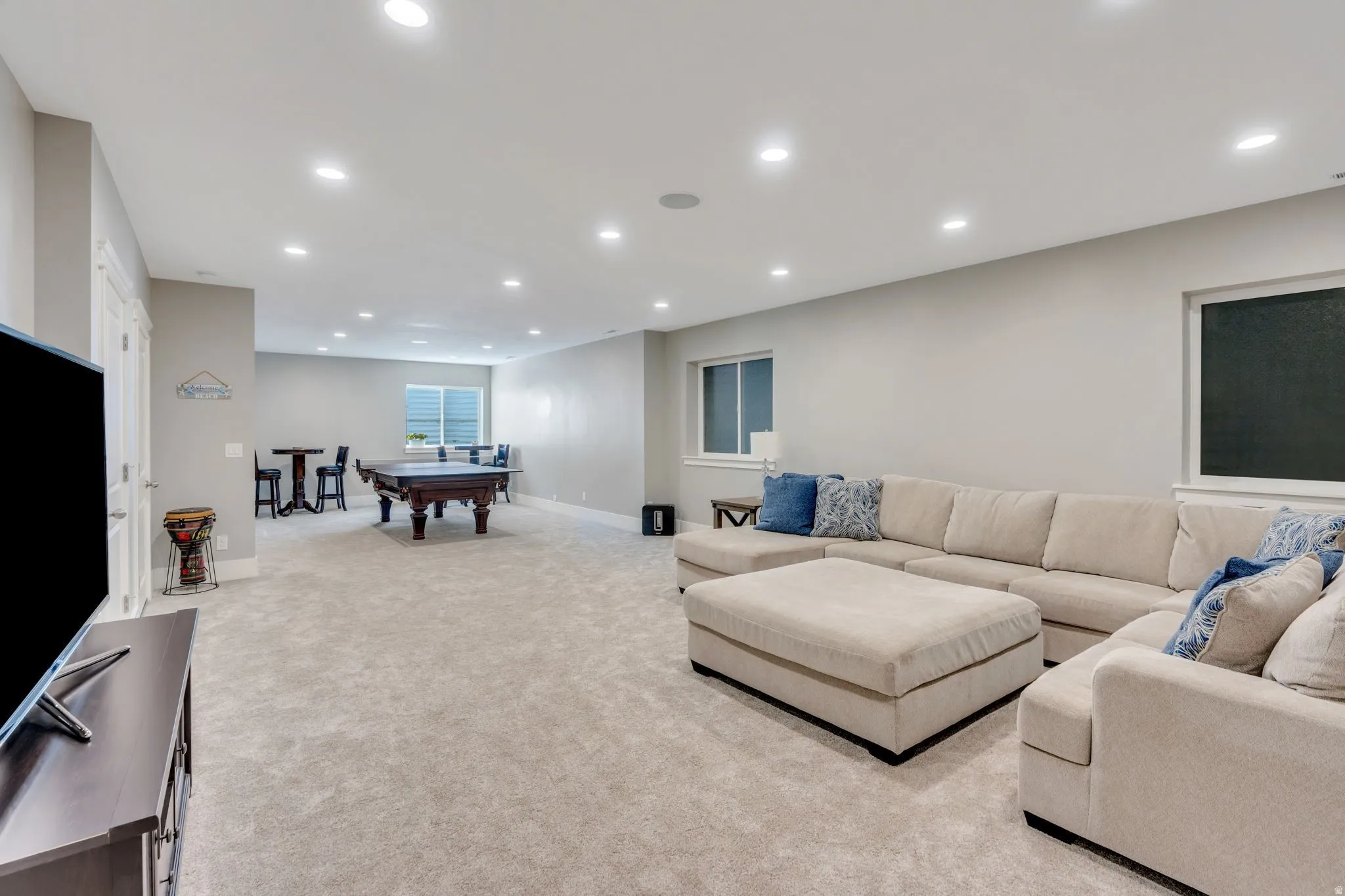 Recessed lighting, light-toned walls, and neutral carpeting create a versatile interior