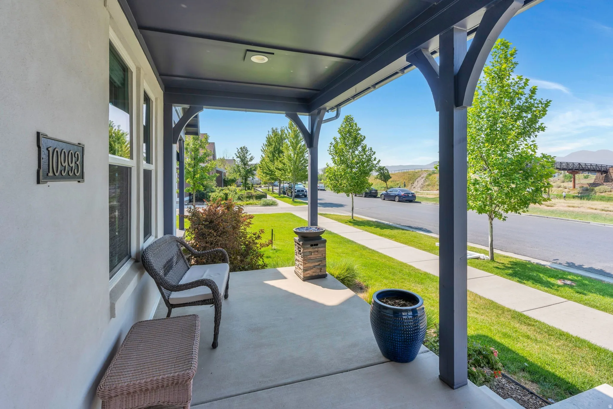 Covered front porch with concrete flooring, dark trim, and recessed lighting