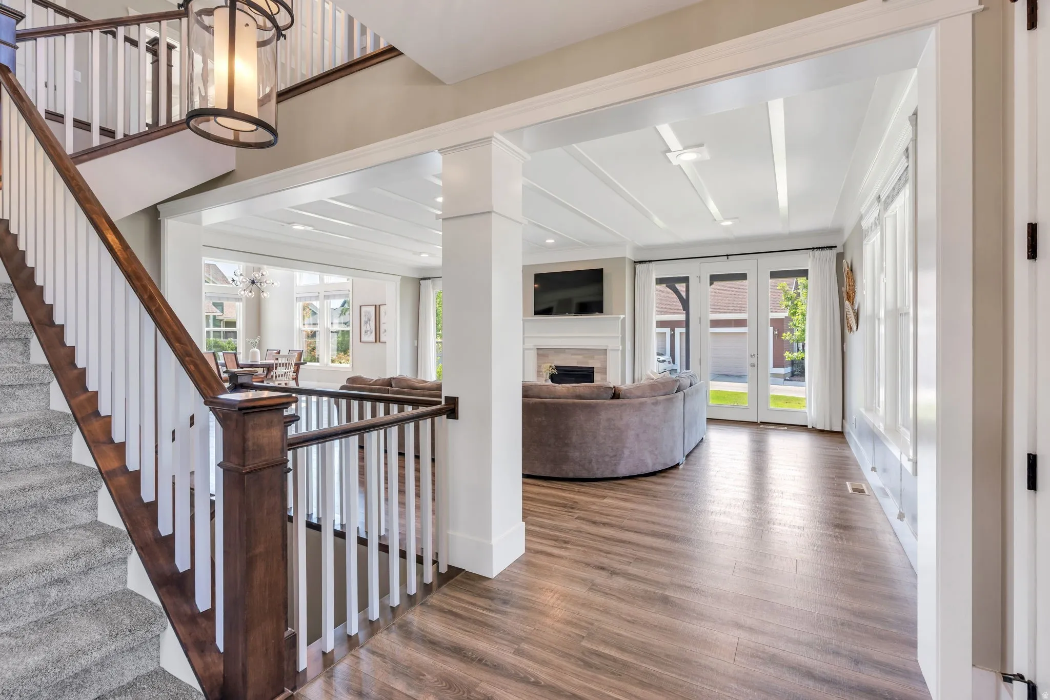 Two-story foyer featuring a wood-finish staircase with white balusters, an elegant overhead light fixture, and wood-finish flooring