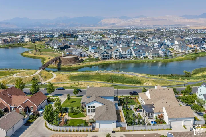 Aerial perspective showcasing a community with a large body of water, a pedestrian bridge, and numerous residential properties