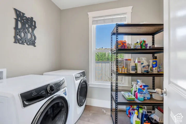 Laundry area featuring light-toned walls, a window with white trim, and tile flooring