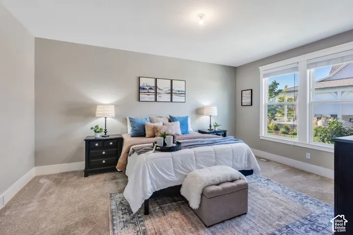 Recessed ceiling lighting, light gray wall paint, two large windows with white trim, and light-toned carpet flooring