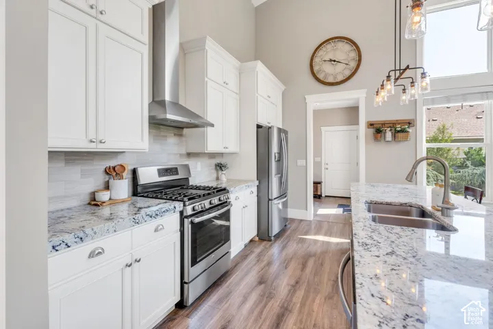 Kitchen featuring white cabinetry, stainless steel appliances, speckled stone countertops, a tile backsplash, and wood-finish flooring