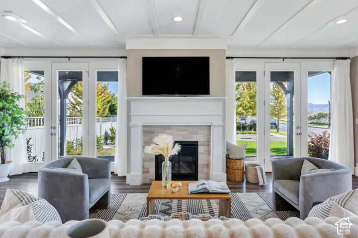 Bright, open living space anchored by a gas fireplace with white surround and mantel, topped with a wall-mounted flat-screen television