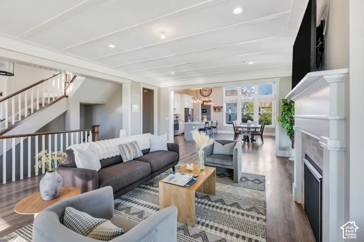 Wood-finish flooring throughout, coffered ceiling, traditional staircase with white balusters, white fireplace with tile surround, and an open concept layout