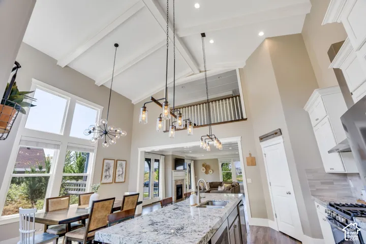 Vaulted ceilings with exposed beams, multiple pendant light fixtures, and an upper-level balcony